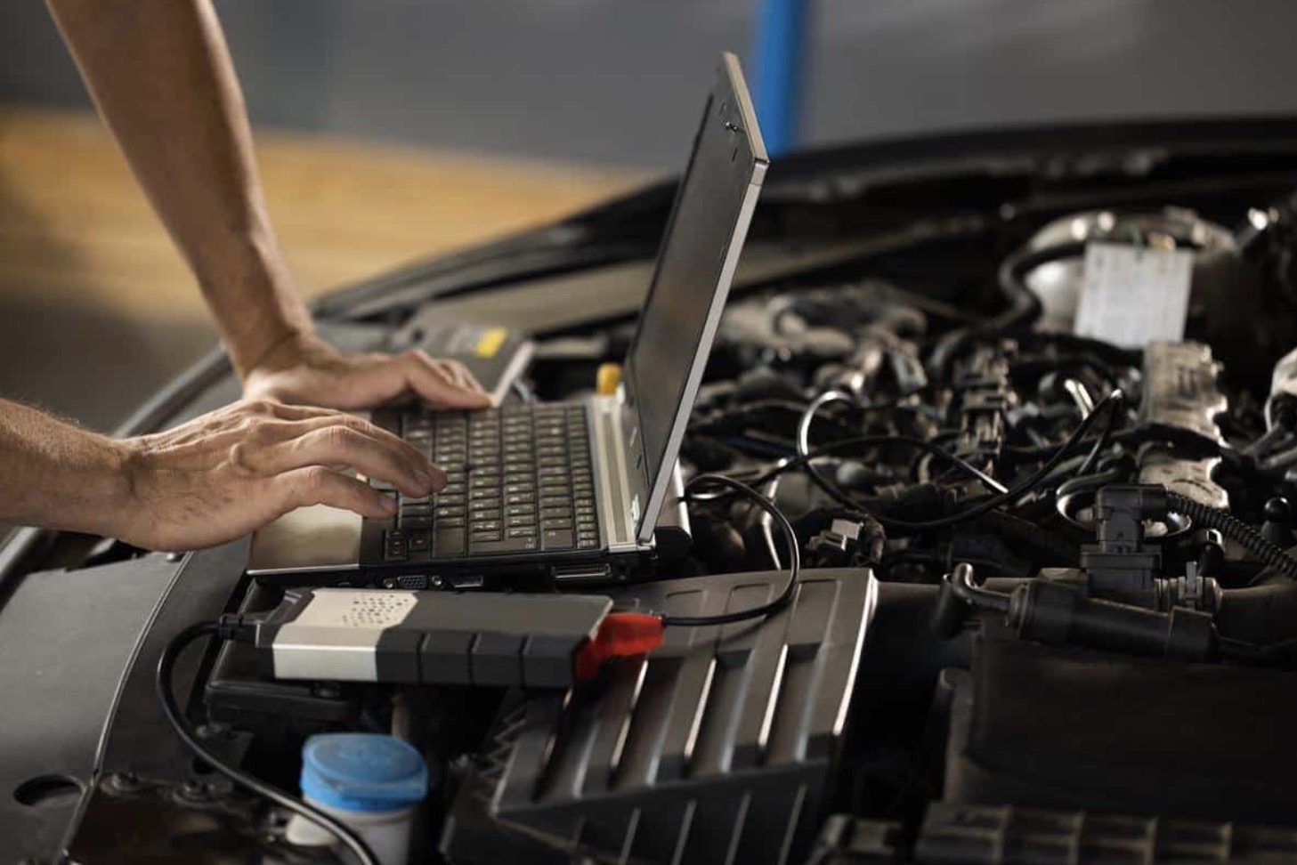 Diagnostic laptop plugged into a car engine bay
